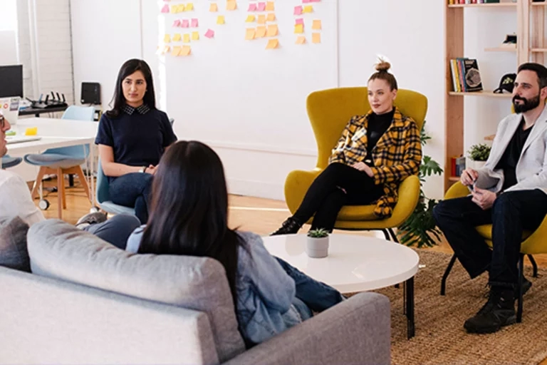 Group of men and women sitting in chairs talking