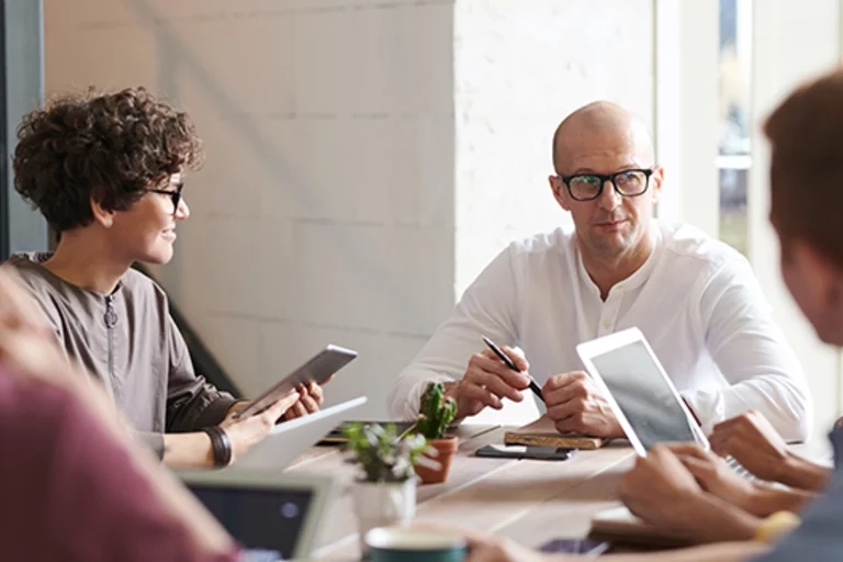 Group of men and women sitting around a conference table talking