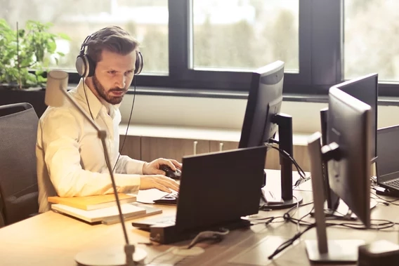 Man wearing a headset working on a computer at a desk