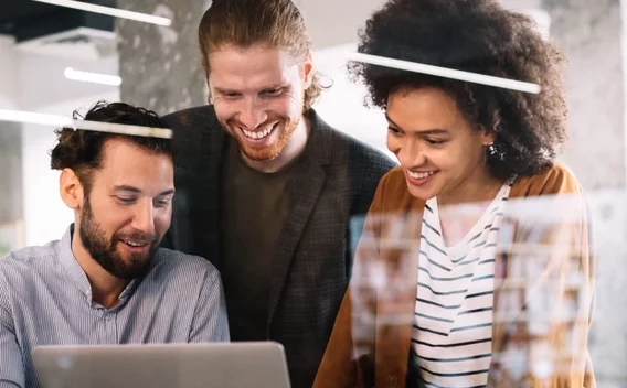 Group of smiling people looking at a laptop screen